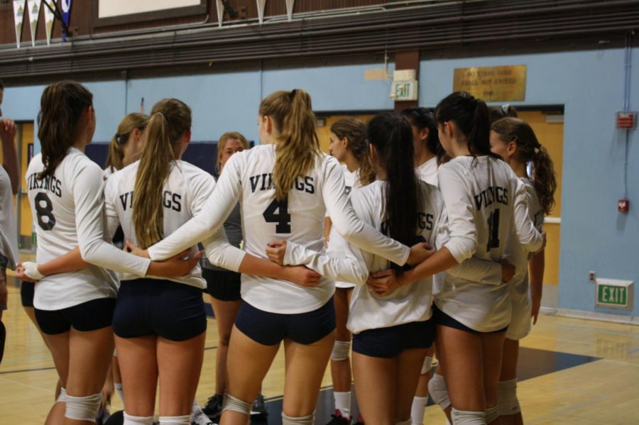 Oakmont girls volleyball team huddling together to plan their next play