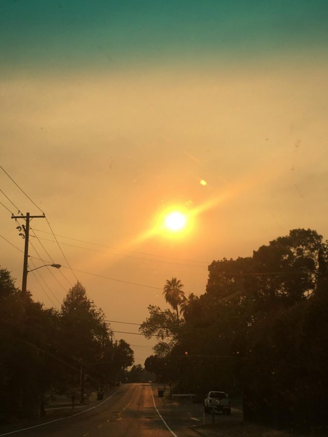 The smoke from nearby wildfires has filled the sky, causing the sun to be crimson red.