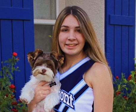 Senior Izzy Perez posing with her dog Teddy in her new cheer uniform.