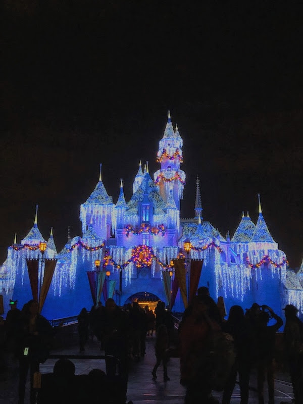 The Disneyland castle dressed up for Christmastime showing the magical appeal of Disney.

