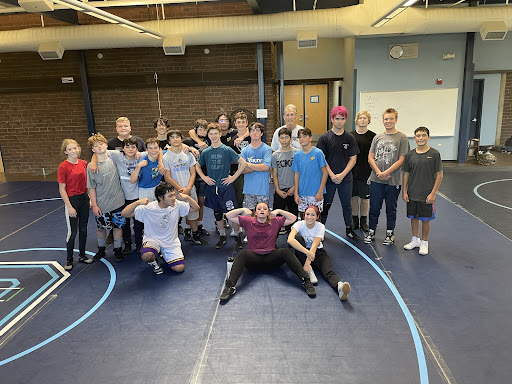 Wrestling team members posing post-practice with Coach Bussey.
