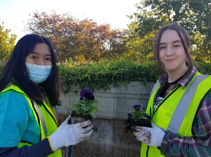 Gabriela Sevilla (left) and Hannah Collier (right) pose for a picture holding flowers they are going to plant.
