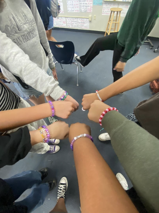 Club members showing bracelets they made together during a meeting.