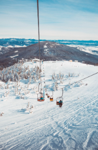People riding a ski lift at a mountain range.