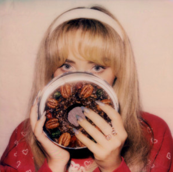 Sabrina Carpenter poses with a fruitcake in a festive Christmas sweater on the cover of her EP, “fruitcake.” 

PC Spotify