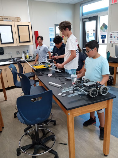 John Carlson, senior, assists camp participants as Dylan Phan, senior, looks on. PC: Christophe Royer