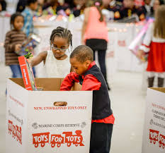 Kids placing toys in the Toys for Tots toy drive box to help other children who are in need. PC: NARA & DVIDS
