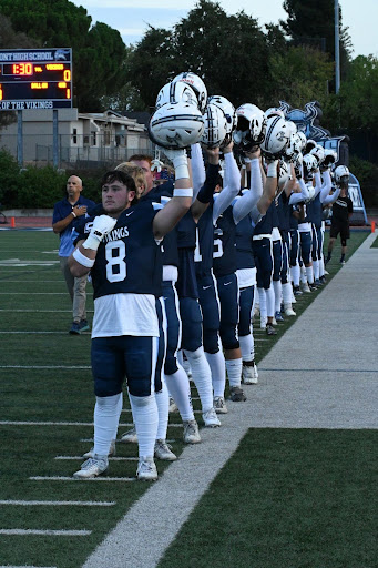 Mac Hughes (12) and the Varsity Football team before the game, during the national anthem. PC: Adelina Eck

