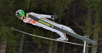 Person in white professionally ski jumping. PC: Wikipedia