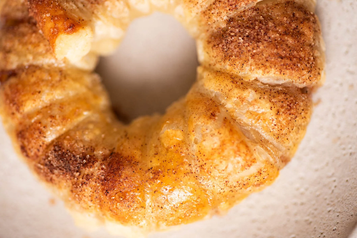 Image of a golden brown baked puff pastry apple donut with cinnamon sugar. PC: Tasty AZ
